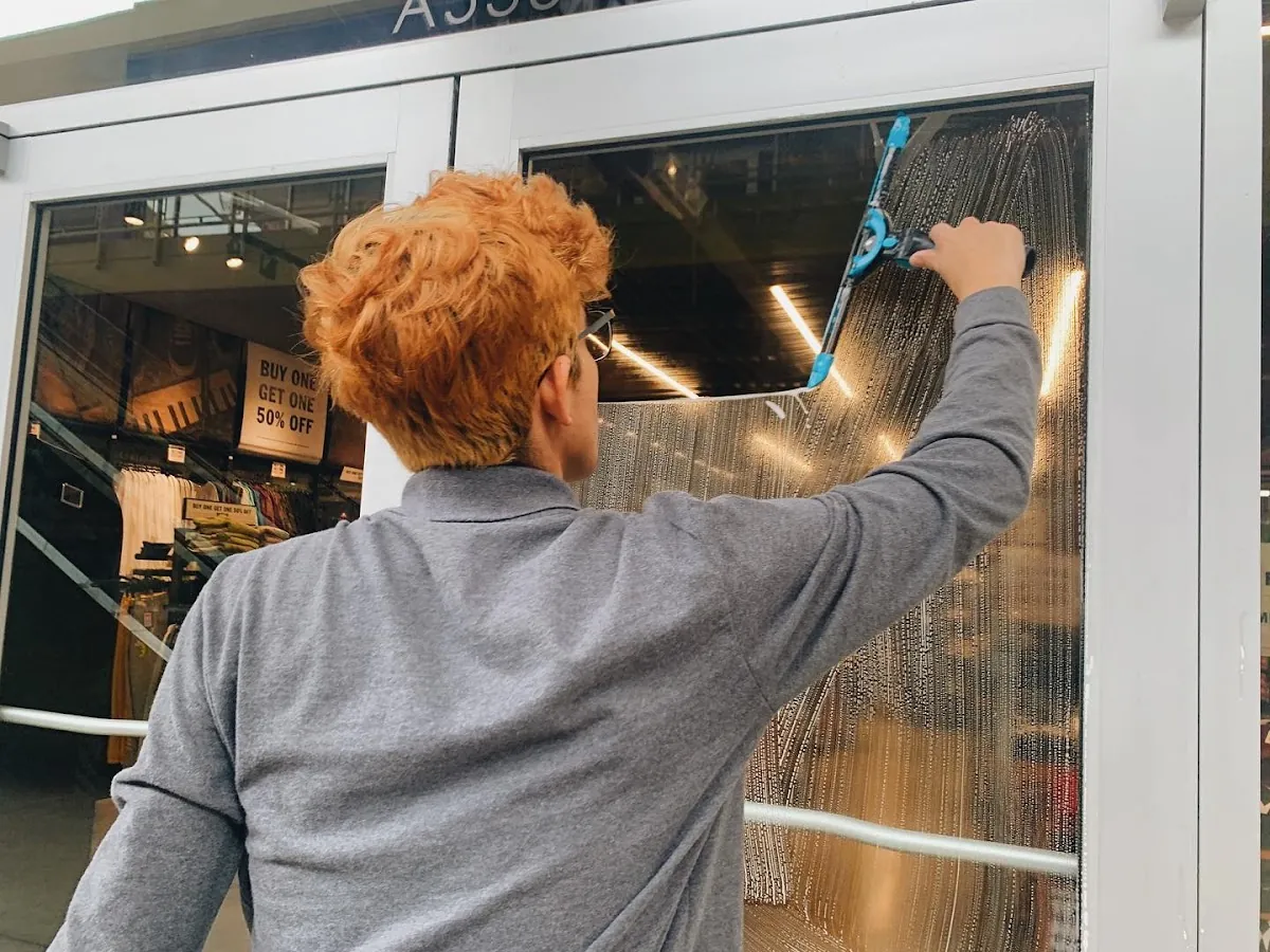 Otto's technician scrubbing a commercial glass door by hand